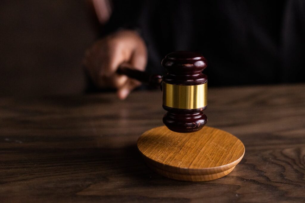 pexels photo 6077326 A gavel striking a sound block, symbolizing justice and legal authority in a courtroom setting.